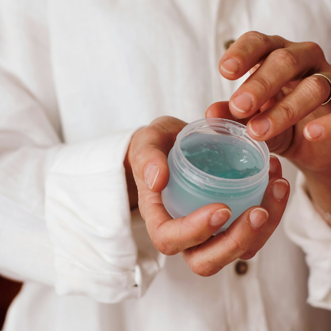 Hand holding an open jar of styling gel